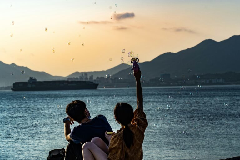 man and woman sitting on beach during sunset