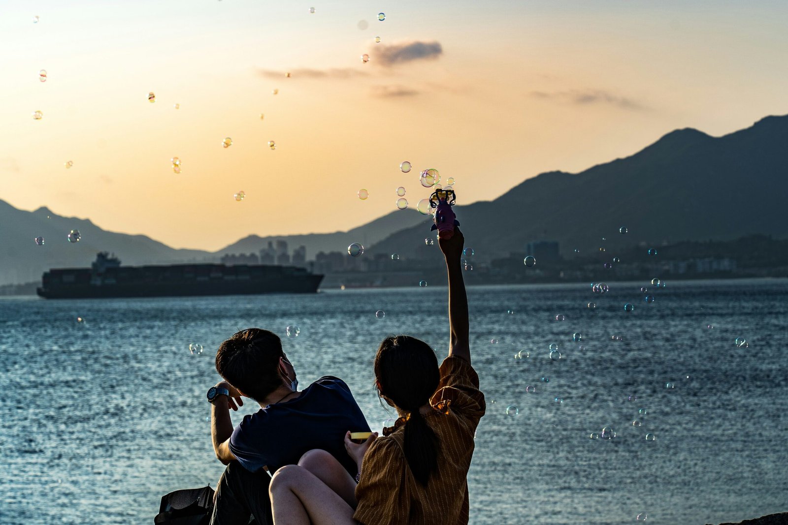 man and woman sitting on beach during sunset